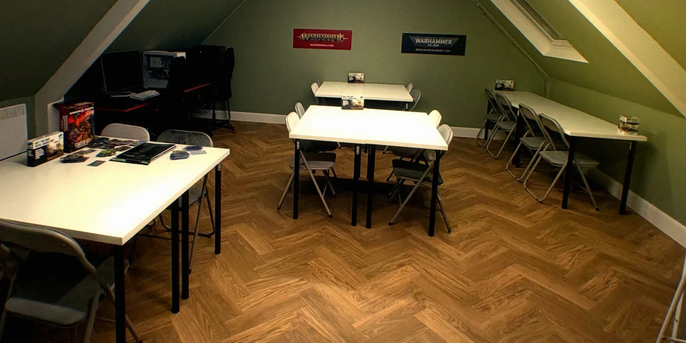 Card tables in the upstairs gaming room, under the Warhammer banners
