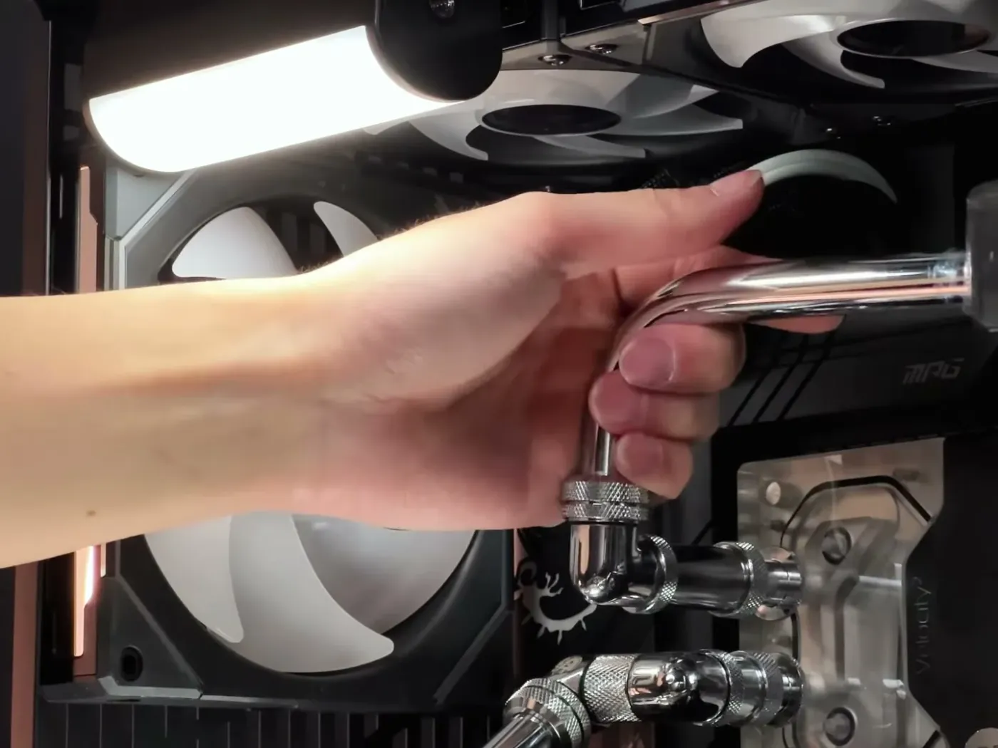 Hands fitting a chrome hardline tube into a water-cooled PC