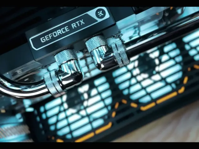 Chrome hardline water cooling fittings on a graphics card block, lit in blue